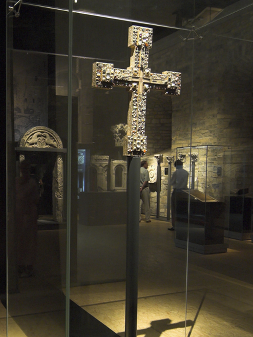 Blick in die Ausstellung "Canossa". Im Vordergrund ein mit Edelsteinen besetztes Vortragekreuz. (öffnet vergrößerte Bildansicht)