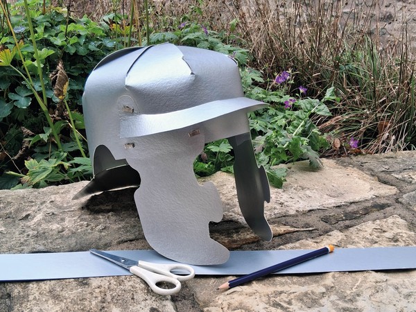 Ein gebastelter Legionärshelm aus Pappe auf einer Mauer.