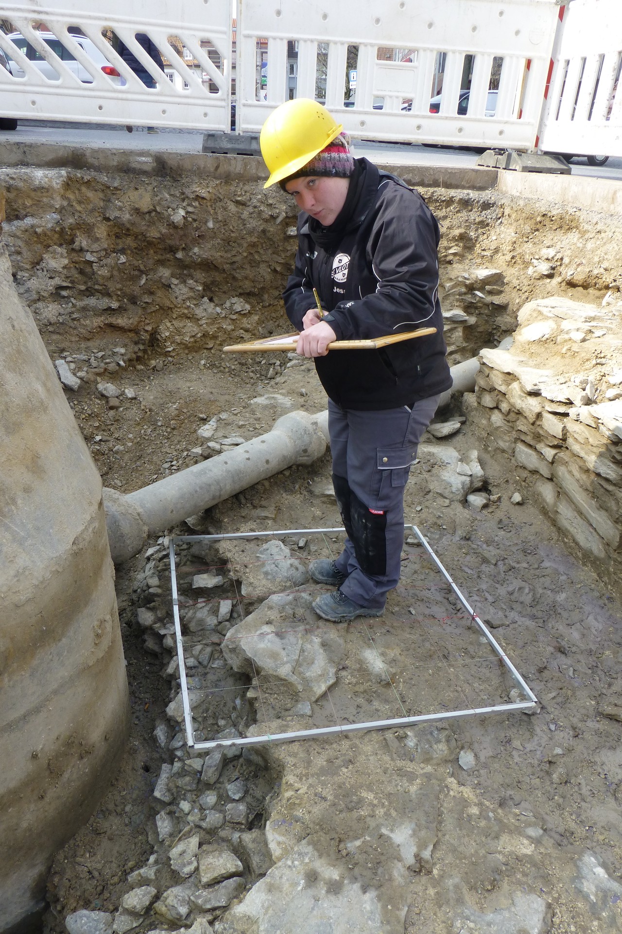 Unter dem in einem kleinen Teil abgetragenen Fundament wird das darunter liegende Pflaster gezeichnet. Foto: LWL/Spiong.
