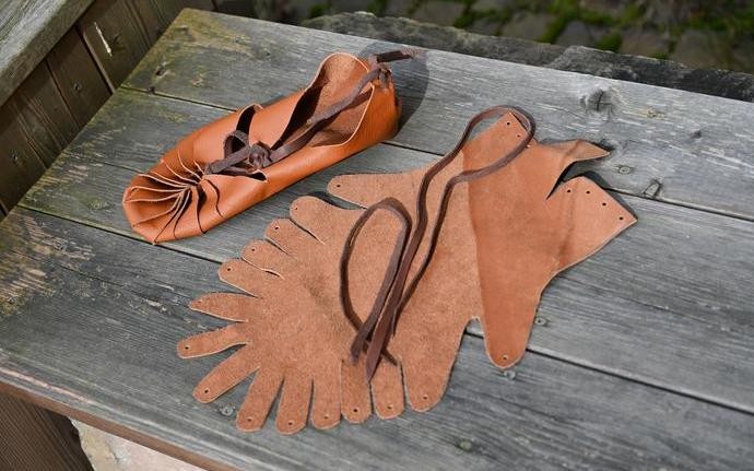 Links ist steht selbst gebastelter Lederschuh, rechts ein Lederstück, das in Form geschnitten ist um zu einem Schuh gebastelt zu werden.