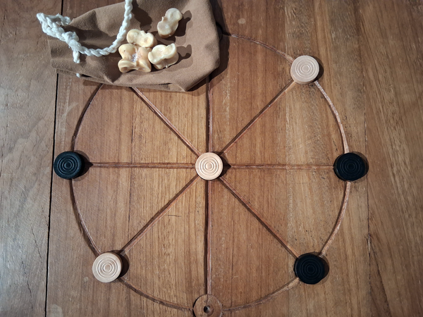 Spielsteine und Knochenwürfel auf einem römischen Rundmühlespiel.