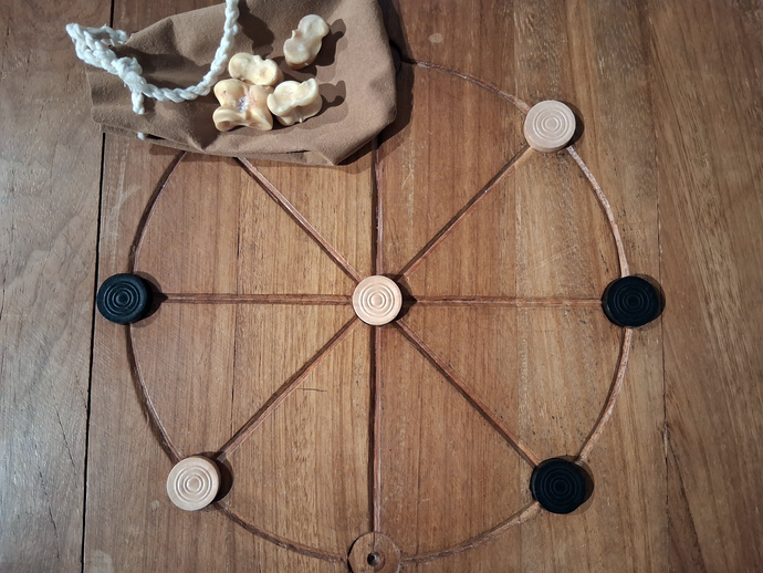 Spielsteine und ein Beute mit römischen Knochenwürfeln auf einem Rundmühlefeld.